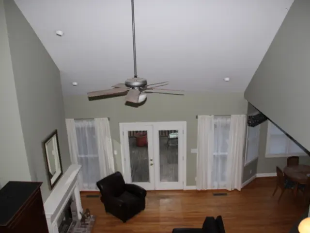 There is a room with a fan hanging and door to access and curtains on the window and dining table...