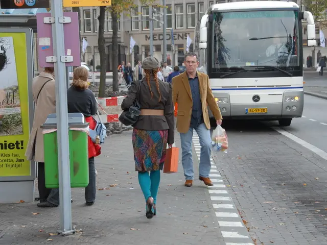 In this picture we can see some men and women walking on the pedestrian path. Beside there is a...