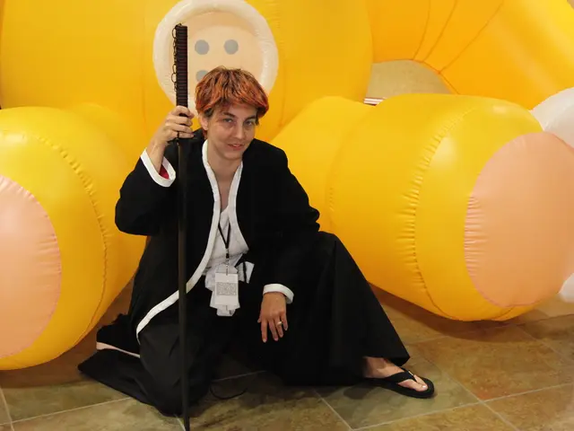 In this picture we can see a person is smiling and holding a stick, in the background there is an...