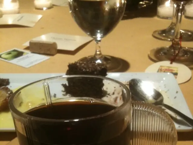 In this image there is a table and on top that there is a cup, saucer, tea, plate, spoon, a...